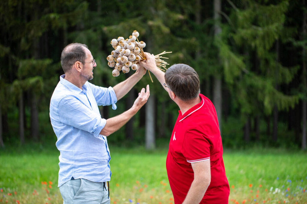 Gerhard Winkler und Mohnbauer Andreas Greßl halten einen Strauß getrockneten Mohns in den Händen.
