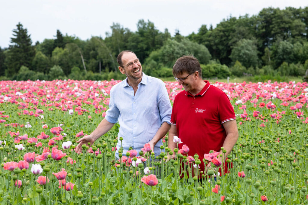 Gerhard Winkler und Mohnbauer Andreas Greßl stehen lachend im Mohnfeld.
